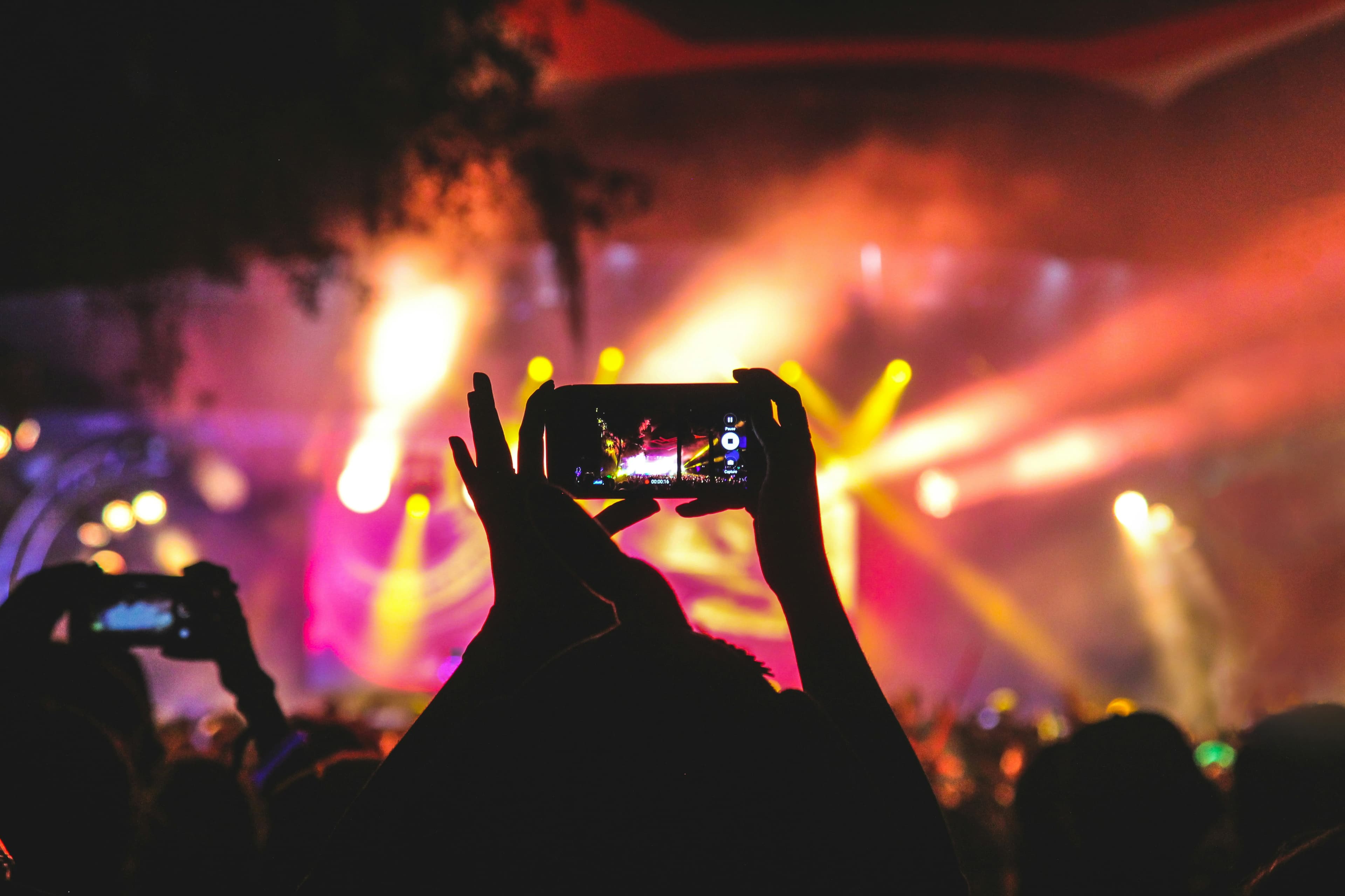 Crowd with raised hands at a colourful night-time festival