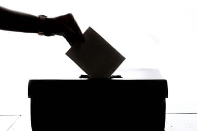 Hand dropping a ballot into a box