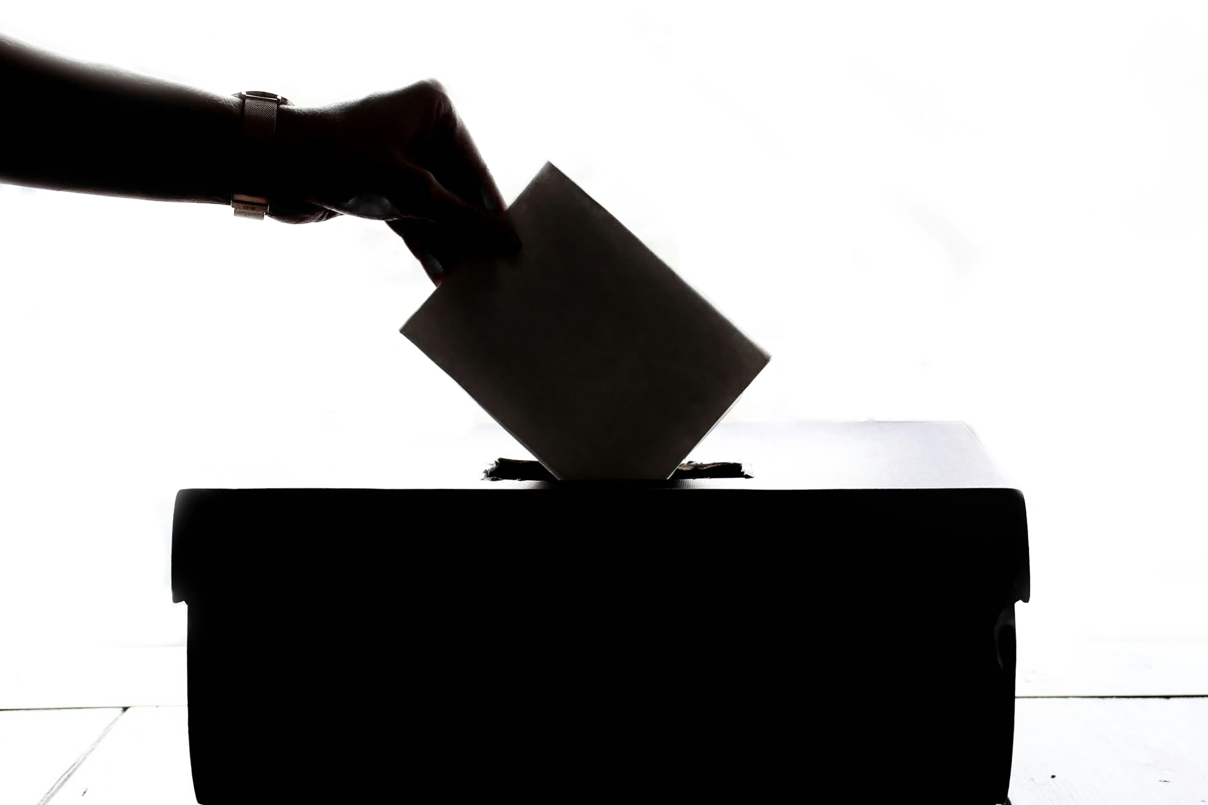 Hand dropping a ballot into a box