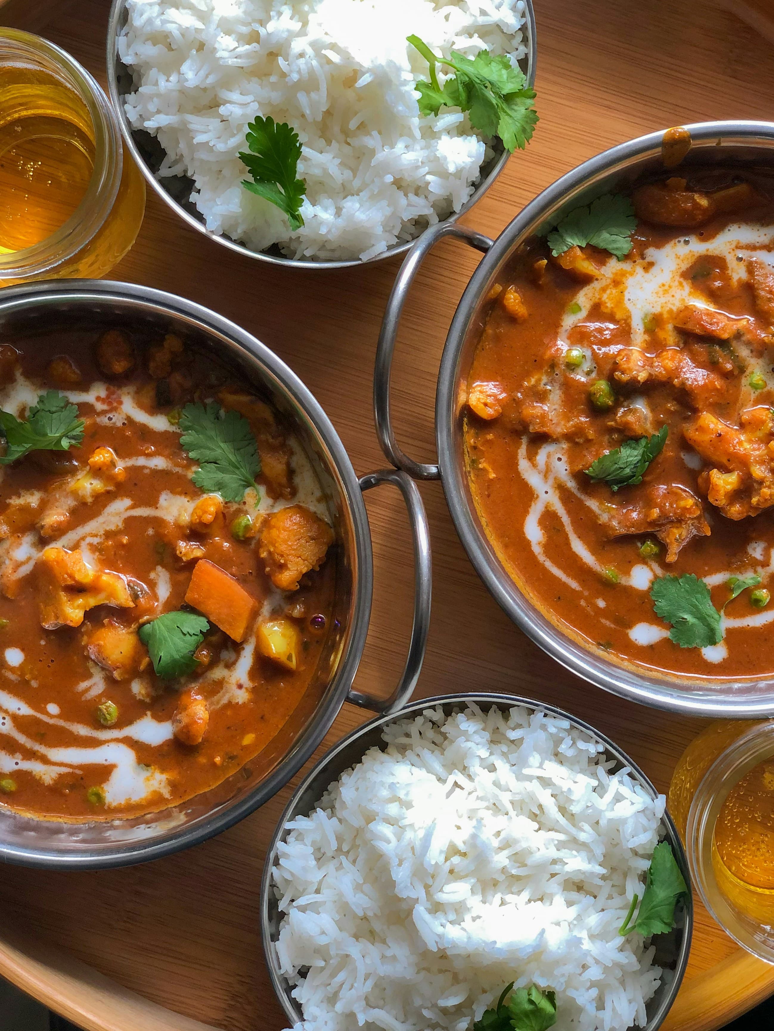 Bowls of curry with rice on a wooden table